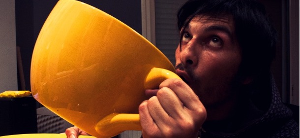 Man drinking enormous cup of coffee (by Christos Kotsakis)