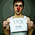 Man-with-clown-nose-sign-saying-Kick-Me